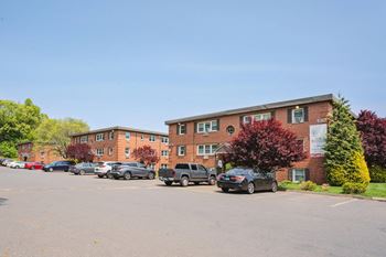 a parking lot with cars in front of an apartment building at Springwood Gardens, Connecticut, 06053